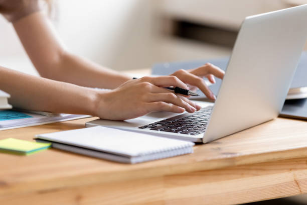 Closeup cropped image student girl hands typing using laptop Cropped close up image woman hands holding pen typing on laptop student do homework prepare essay make research, businesswoman communicate online with client solve business questions distantly concept child using laptop stock pictures, royalty-free photos & images