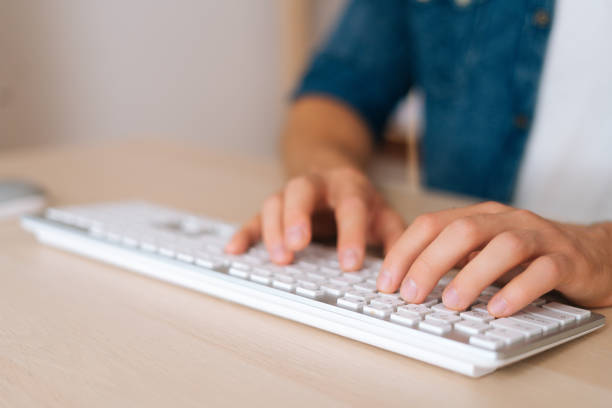 Close-up front view hands of unrecognizable young business man working typing online message using wireless computer keyboard, stock photo