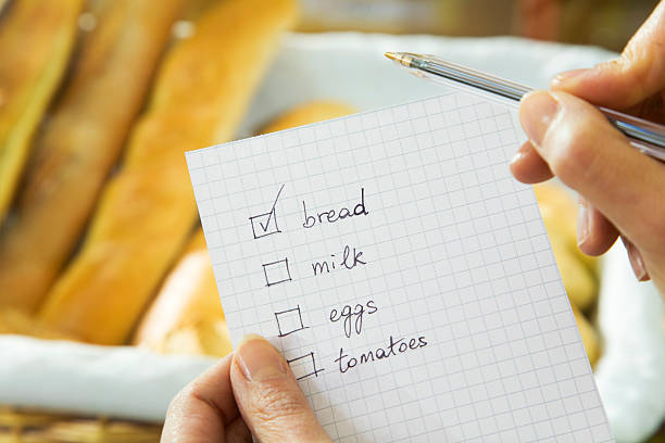 Close-up Grocery list bread checked off with baguettes woman in a supermarket checking his shopping list shopping list stock pictures, royalty-free photos & images