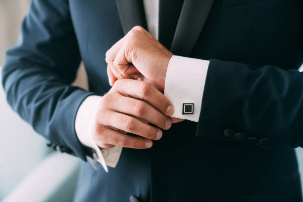 Close-up groom hands puts on cufflinks. Elegant gentleman clothes, white shirt stock photo