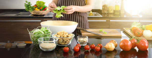 Closeup hand mix the vegetables in a salad bowl. Morning atmosphere in a modern kitchen. stock photo