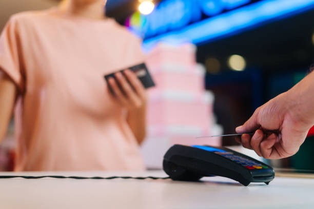 Close-up hands of unrecognizable male customer paying with NFC technology by credit card contactless on POS terminal, selective focus. stock photo