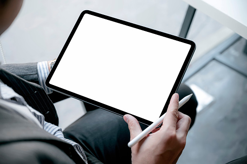 Closeup image of businessman hand holding digital table with blank screen while sitting at office.