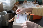 女性オンラインストア中小企業経営者の起業家が梱包パッケージを梱包し、テーブルの上に配達小包を準備するポスト配送ボックスのクローズアップ画像。