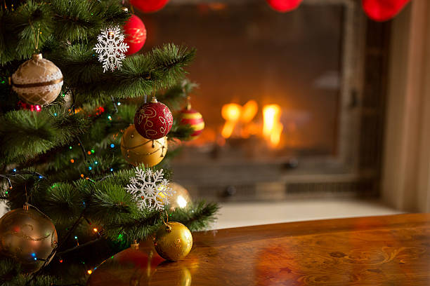 closeup image of golden baubles on christmas tree at fireplace - christmas tree stok fotoğraflar ve resimler