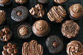 Stock photo showing cooling rack of homemade chocolate cupcakes topped with piped chocolate icing frosting in paper cake cases.