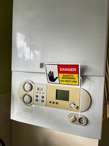 Stock photo showing close-up view of a gas, combi boiler with a 'Do Not Use' warning sign.