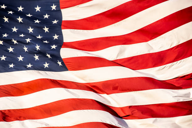 Closeup large American flag blowing in wind stock photo