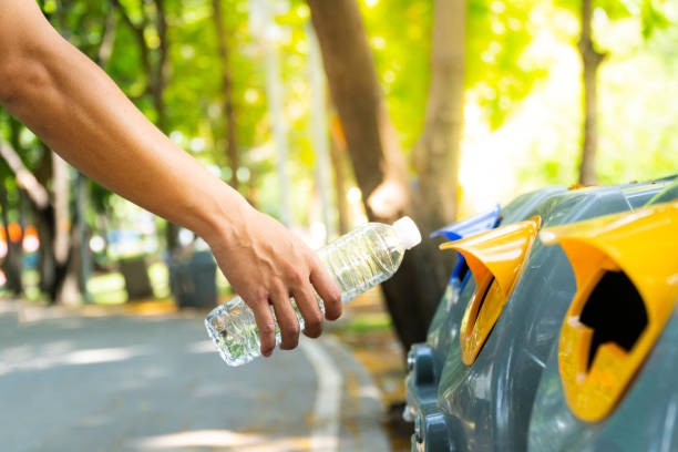 Closeup man hand throwing empty plastic water bottle into to recycling bin, environmental protection concept. stock photo