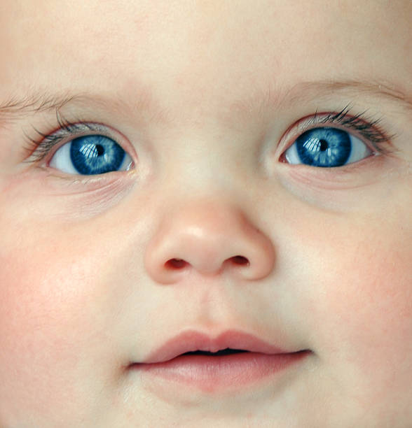 Close-up of a baby's face and blue eyes stock photo