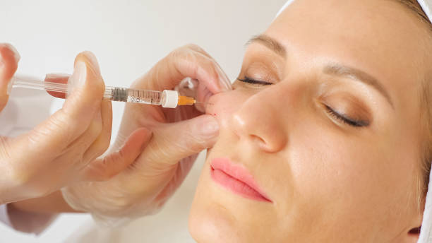 Close-up of a beautician giving an injection into the cheek of a woman stock photo