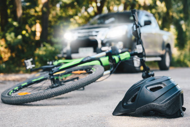 Close-up of a bicycling helmet fallen on the asphalt next to a bicycle after car accident on the road. stock photo