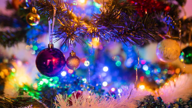 Close-up of a branch of Christmas tree with tinsel and colorful baubles stock photo