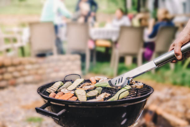 Closeup of a charcoal round barbecue grill and vegetables being grilled stock photo
