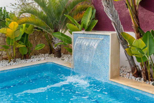 Close-up of a fountain waterfall in a luxury pool near the hotel with palm trees for tourists. stock photo