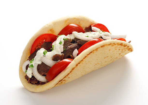 Close-up of a Gyros or Doner Kebab on white background High-resolution digital capture of a freshly prepared Gyros or Doner Kebab; with shaved meat, tomatoes, onions, chives and tzatziki sauce, on fresh pita. Shot on a clean white background with a soft and subtle shadow. shawarma stock pictures, royalty-free photos & images