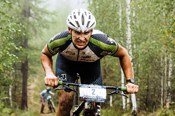 closeup of a male cyclist rides through forest stock photo