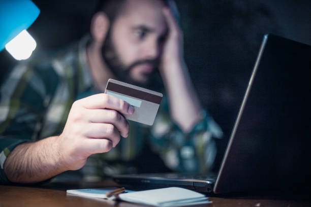 Close-up of a man paying bills from home by using a laptop and a credit card Close-up of a man paying bills from home by using a laptop and a credit card student loan stock pictures, royalty-free photos & images