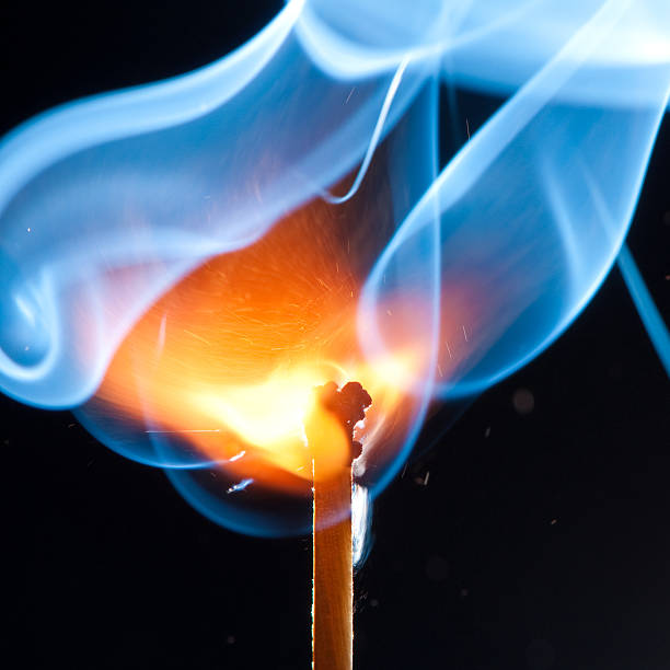 Close-up of a match igniting with red and blue flames stock photo