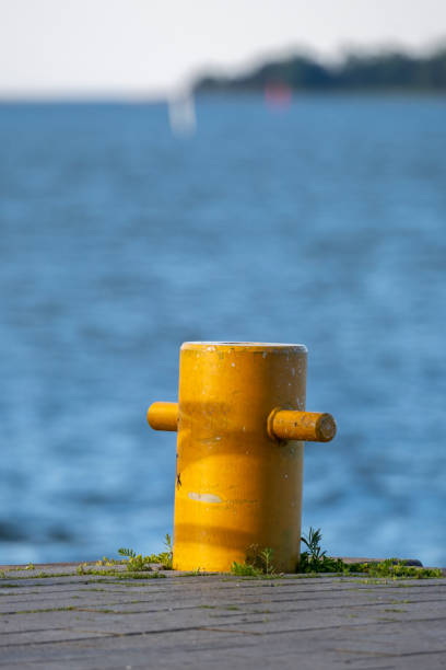 Closeup of a mooring bollard against a bright blue sea. A small island in the horizon. stock photo