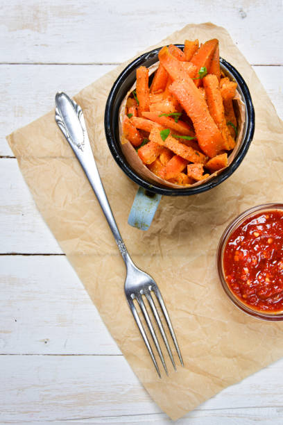 Close-up of a mug full of healthy carrot fries and hot chili dip. stock photo