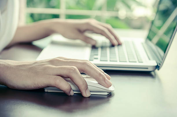 Close-up of a person using a laptop and mouse stock photo