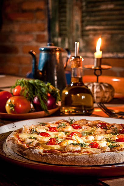 Close-up of a pizza on a tray next to jug of oil and candle Pizza with food in the background muenster cheese stock pictures, royalty-free photos & images