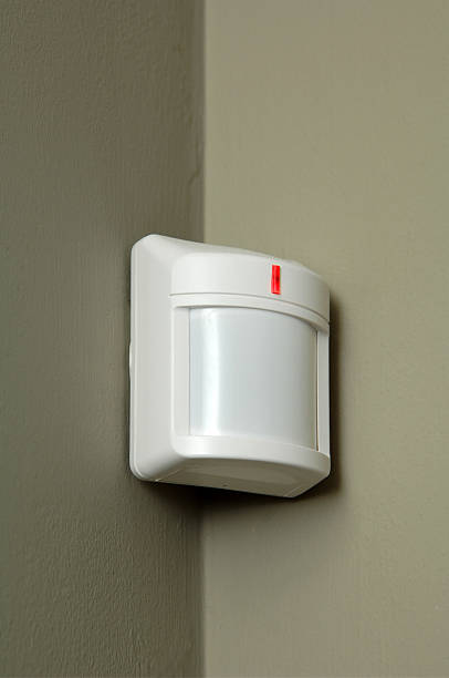 Close-up of a white motion detector on a gray wall stock photo