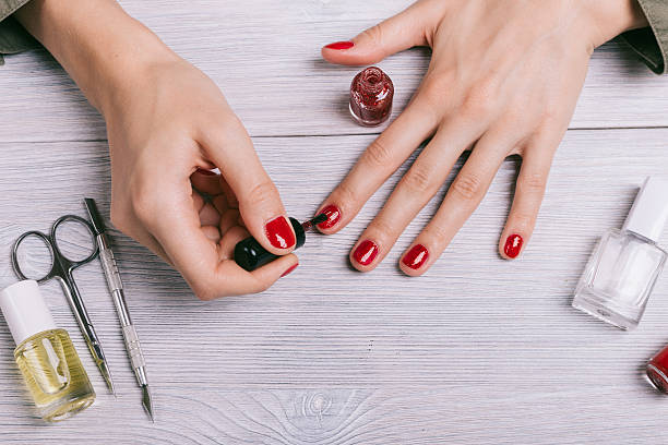 Close-up of a woman paints her nails with red lacquer Close-up of a woman paints her nails with red lacquer painting fingernails stock pictures, royalty-free photos & images