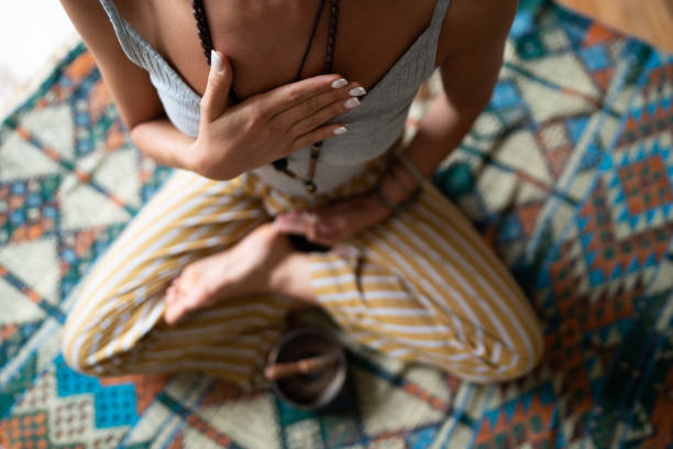 Close-up of a woman's hand on her chest while doing breathing exercises Close-up of a woman's hand on her chest while doing breathing exercises and meditating at home. Caucasian woman sitting in a lotus position, practicing pranayama. inhaling stock pictures, royalty-free photos & images
