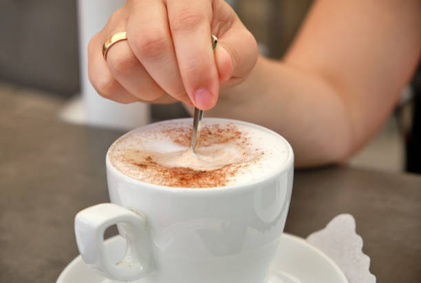 Closeup of a woman's hand stirring her cappuccino stock photo