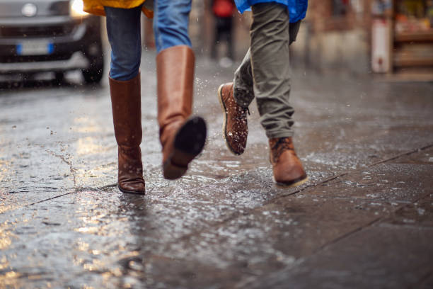 Close-up of a young couple and their legs how walking on the rain in the city. Walk, rain, city, relationship stock photo