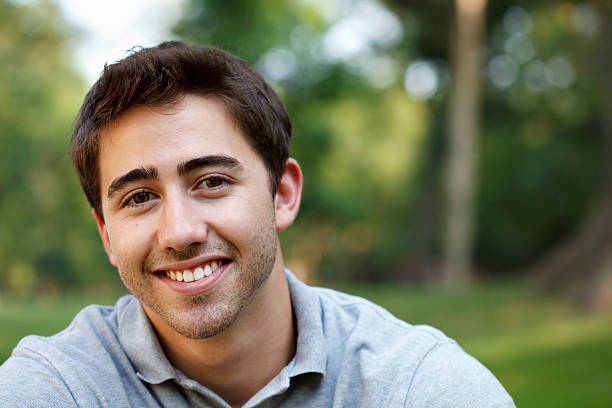 Close-up of a young man smiling Portrait of an early 20s young man in the park. 20 24 years stock pictures, royalty-free photos & images