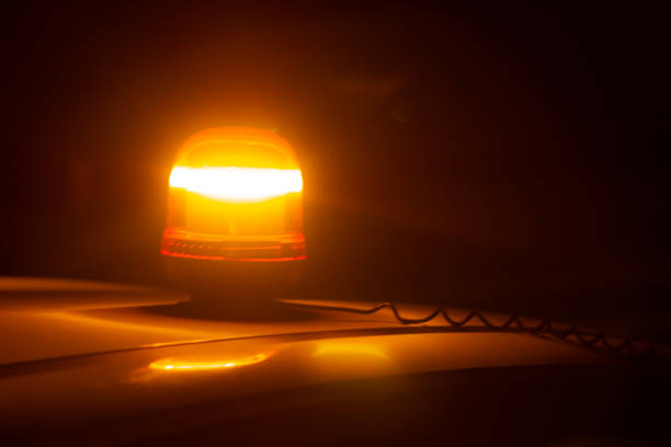 Closeup of an amber strobe warning light on the roof of a car at night stock photo