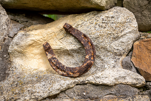An old rusty horseshoe propped on a big stone. Symbol of happiness and luck.