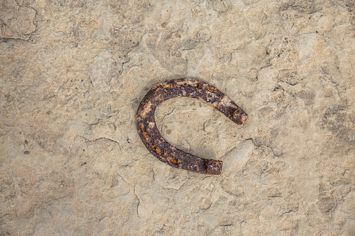 An old rusty horseshoe propped on a big stone. Symbol of happiness and luck.