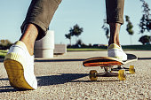 istock Closeup of black legs riding skateboard in park 1349788139