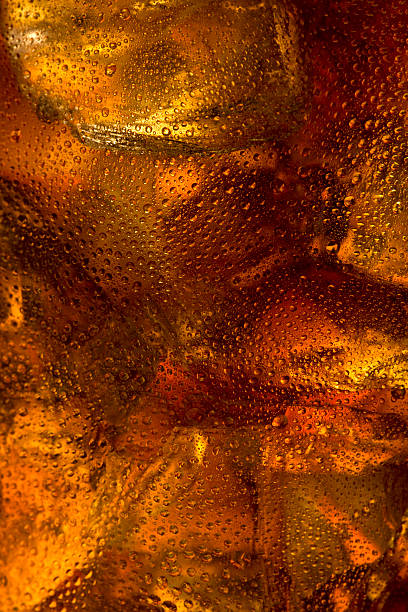 Close-up of cola with ice cubes inside a glass cup Close up of ice floating in a glass of cola. Detailing shows condensation and melting ice along with the refreshing bubbles in the drink itself. cola stock pictures, royalty-free photos & images