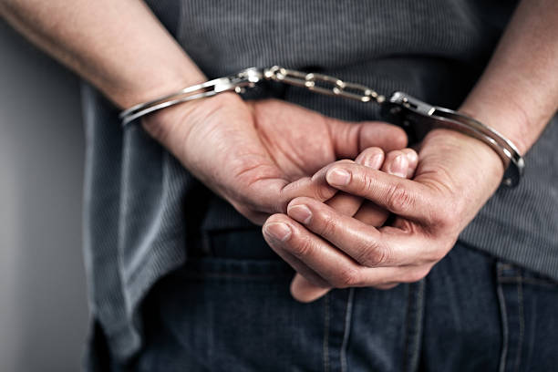 Close-up of cuffed criminal hands Arrested man in handcuffs with hands behind back restraining stock pictures, royalty-free photos & images