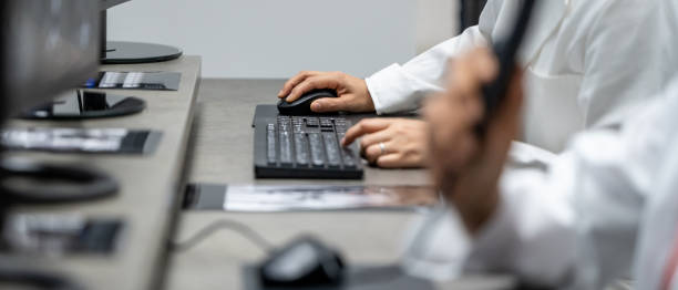 Close-up of doctor's hands while using computers and dictaphone stock photo