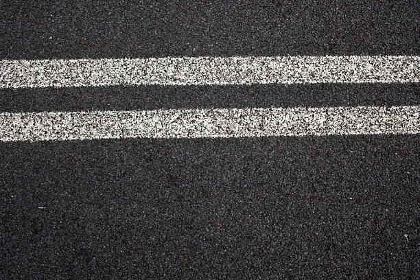 Close-up of double white lines on pavement An elevated view shot of double white lines on a road. dividing line road marking stock pictures, royalty-free photos & images