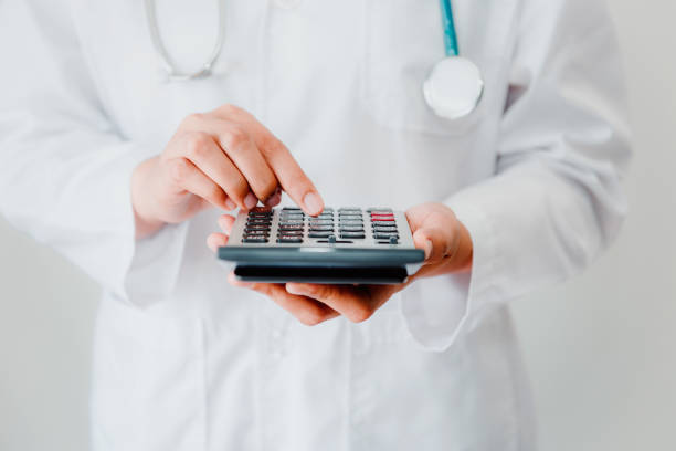 Close-Up of Female Doctor is Calculating Medicine Cost in Office Hospital, Female Medical is Using Calculator. Healthcare and Financial Concept stock photo