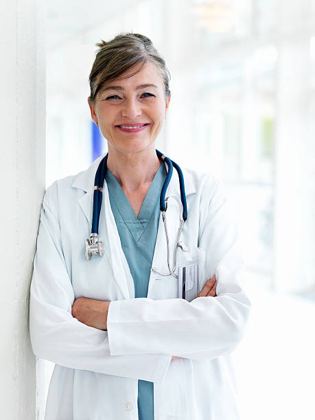 close-up de mulher médico inclinar-se pela parede com braços cruzados - doctor wall imagens e fotografias de stock