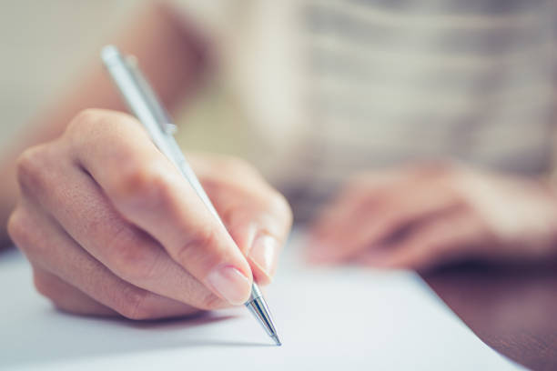 Close-up of female hands, signing paper document in the office stock photo
