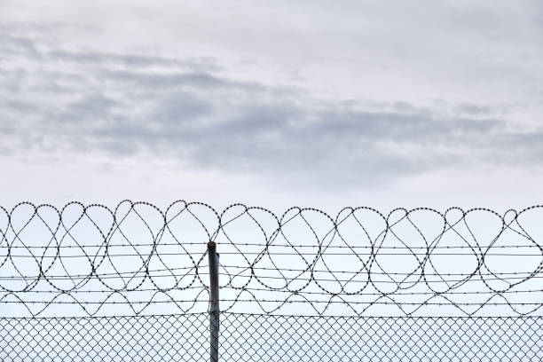 Close-up of fence with razor-barbed wire against sky stock photo