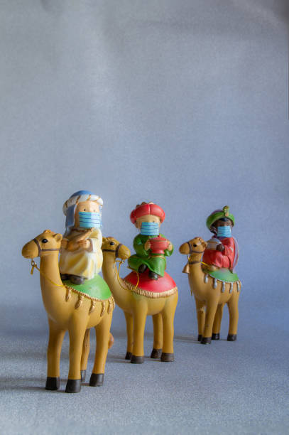 Close-up of figures of the Three Wise Men from the East, with a hygienic mask to protect themselves from Covid-19. Concept of Christmas, safety and precaution against Covid-19. Vertical and copy space stock photo