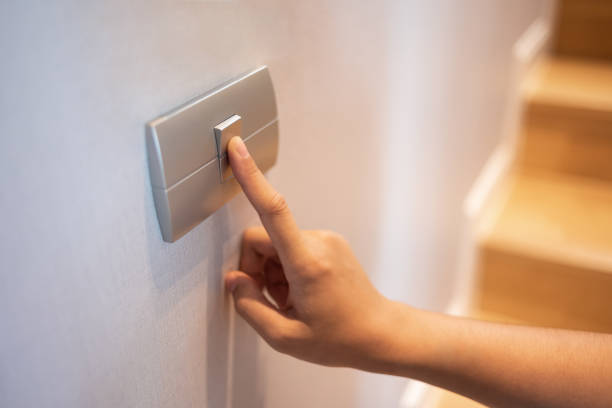 el primer plano del dedo se enciende o apaga el interruptor de luz en la casa. - interruptor fotografías e imágenes de stock