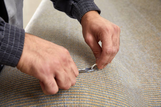 Closeup of hand cutting off string on a carpet with scissors. Carpet cleaning service stock photo