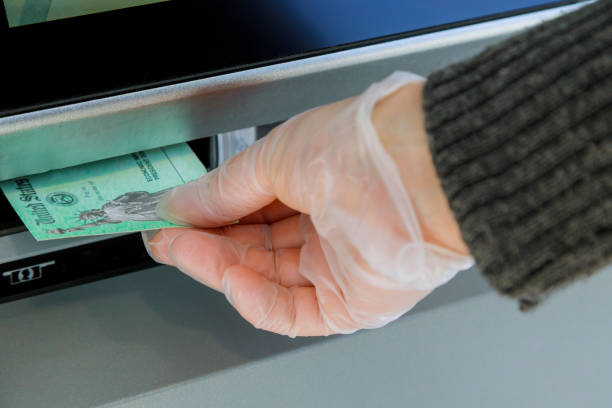 Closeup of hand entering deposit stimulus check to ATM machine transfer Close up of hand entering deposit stimulus check to ATM machine transfer stimulus check stock pictures, royalty-free photos & images