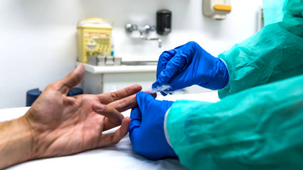 primo piano delle mani di un infermiere con attrezzature di protezione individuali e paziente, nel processo di raccolta del sangue per fare un rapido test per covid-19(coronavirus), in un reparto ospedaliero con elementi sanitari sullo sfondo. - cuadrado foto e immagini stock